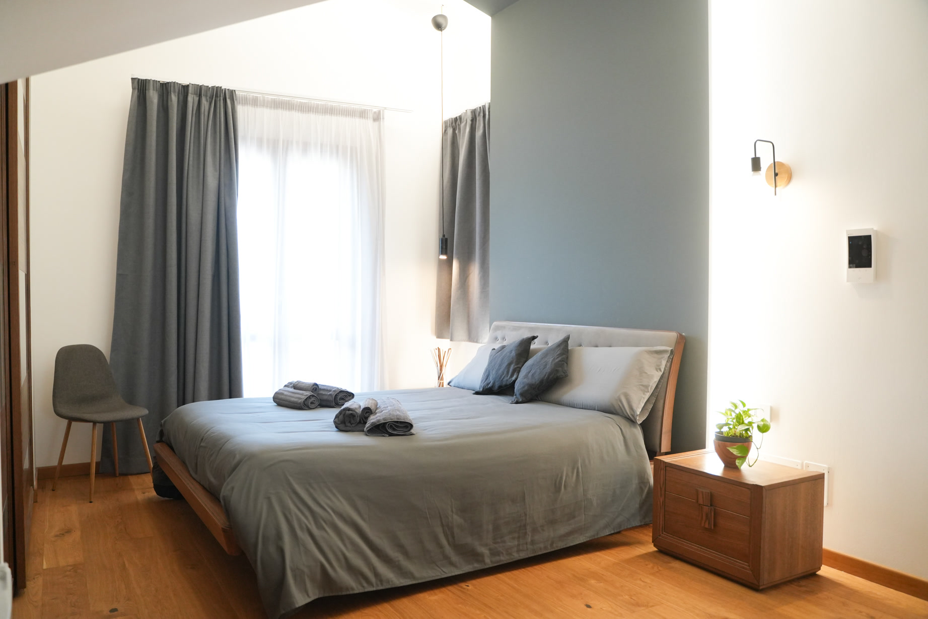 Camera di Theros & Icaro: letto con testiera imbottita, legno chiaro e luce naturale