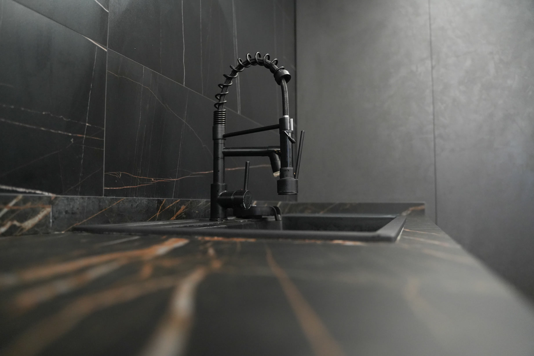 Rubinetto nero su piano cucina in marmo nero venato d'oro