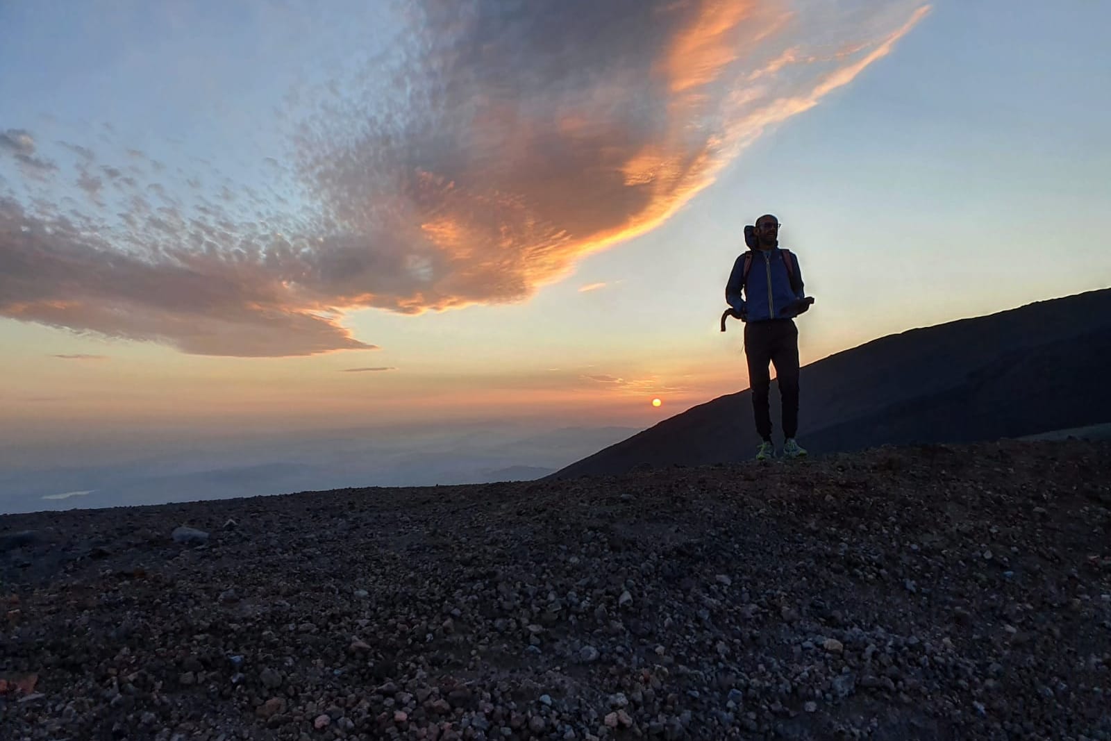 Una figura sul crinale sotto le nuvole accese del tramonto