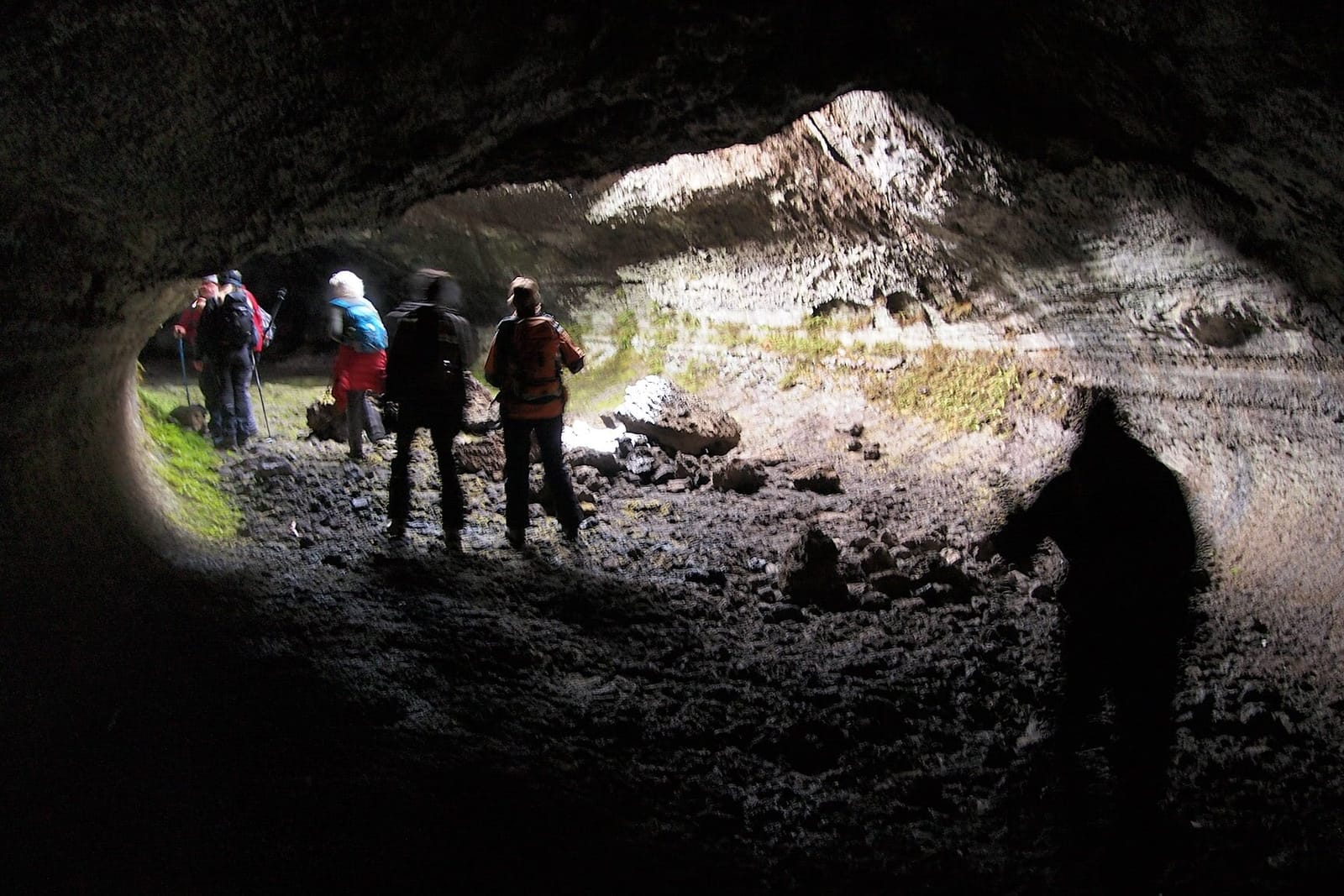 Escursionisti in controluce all'imbocco della grotta di scorrimento lavico