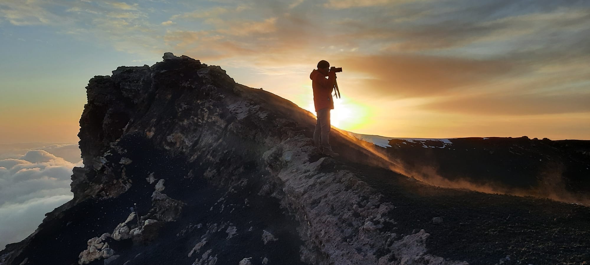 L'ultima luce del giorno dal cratere, un escursionista fotografa il tramonto
