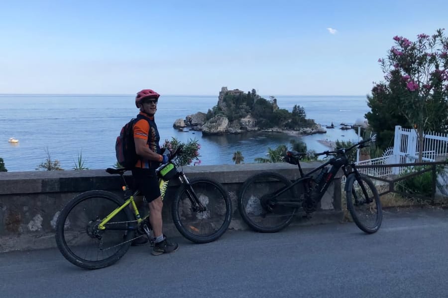 Ciclista con la MTB davanti a Isola Bella, il mare di Taormina