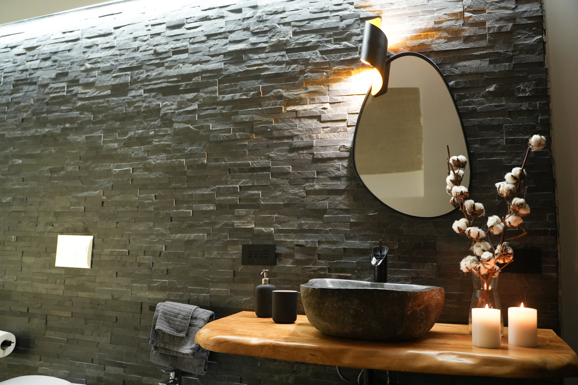 Lavabo in pietra con fiori di cotone e candele accese